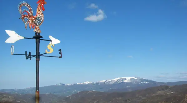 Gallo segnavento su sfondo di montagne innevate in Valmarecchia. Scopri cosa vedere in questa splendida cornice naturale.