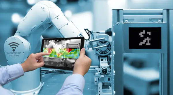 Un braccio robotico e un tablet mostrano l'interfaccia di una macchina automatizzata, illustrando cos'è l'industria 4.0.