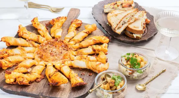 Un apéro réussi : tarte feuilletée en forme de soleil, mini sandwichs, verrines et coupes de champagne. Idéal pour savoir quoi apporter pour une invitation à un apéro.
