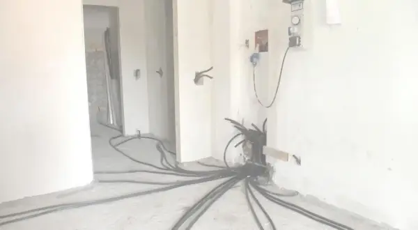 Rifacimento impianto elettrico in corso. Cavi neri si diramano dal muro, pronti per la manutenzione ordinaria o straordinaria.