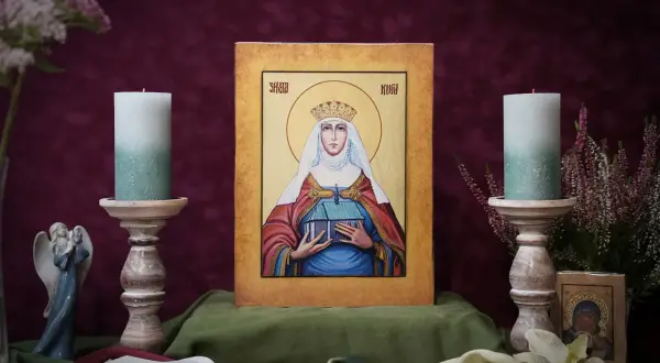 Ikona Świętej Łucji z koroną i budowlą w dłoniach, otoczona świecami i kwiatami.