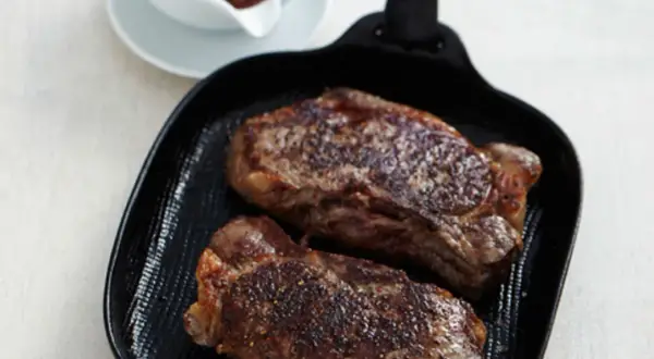 Zwei saftige Rumpsteaks braten in einer Grillpfanne, perfekt gewürzt und mit einer köstlichen Kruste.