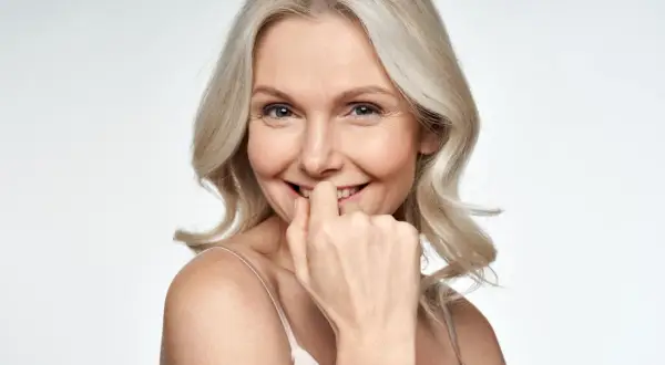 Uśmiechnięta kobieta z blond włosami, która lekko przygryza palec. Czy to fiksacja?