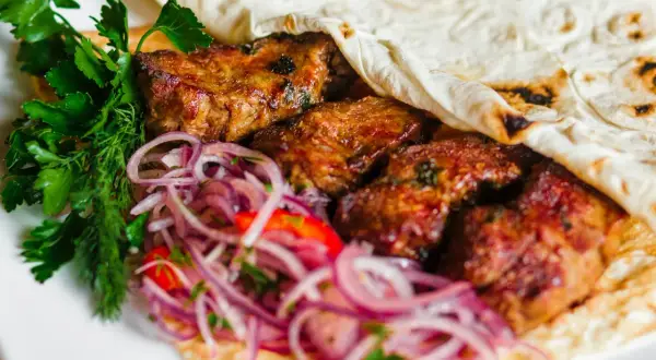 Kebab z mięsem, cebulą i ziołami zawinięty w placek.