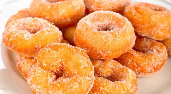 Montón de rosquillas caseras de toda la vida, doradas y espolvoreadas con azúcar.