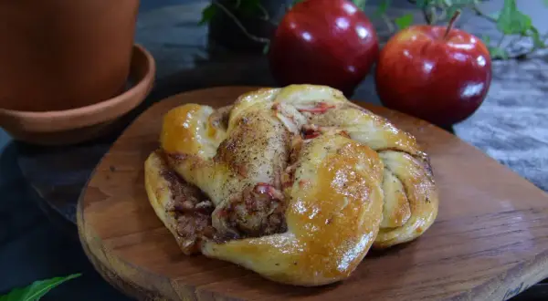 En gyllene kanelbulle med äppelbitar, redo att avnjutas.