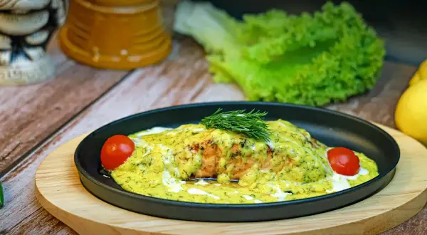 En läcker bit djupfryst lax i ugn, täckt med en krämig sås och dill, garnerad med körsbärstomater och färsk dill.
