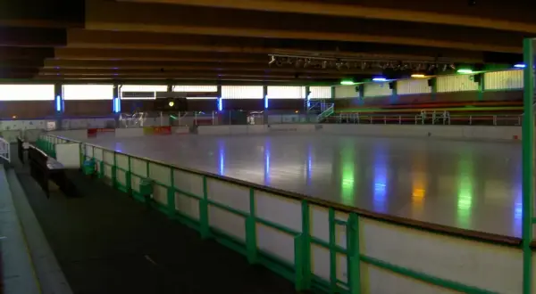 Leere Eisfläche in der Eissporthalle Bergisch Gladbach, beleuchtet von bunten Lichtern.