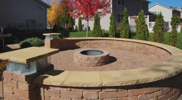 A circular brick patio features an in-ground fire pit, perfect for cozy evenings.