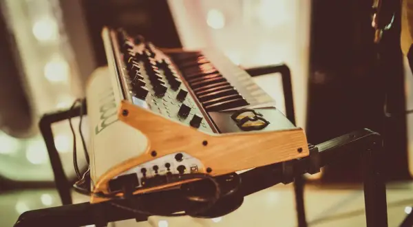 Drewniany stojak na keyboard z czarnymi metalowymi elementami, gotowy do muzycznej sesji.