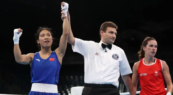 A boxer in a blue uniform with the Chinese flag raises her arm in victory as a referee holds it up. The question of what weight class is 150 in boxing is on many minds.