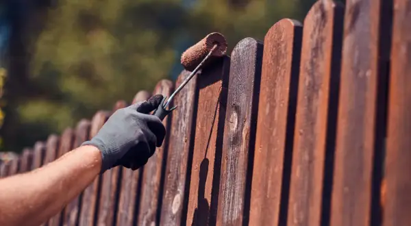 Aplicando protector a la valla de madera para saber como tratar la madera para que no se pudra.