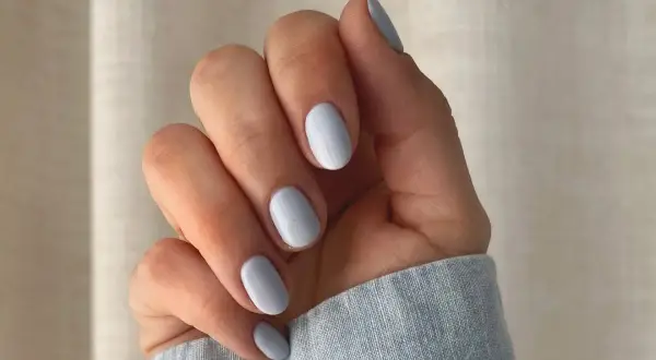 Dłoń z paznokciami w delikatnym baby blue kolorze.