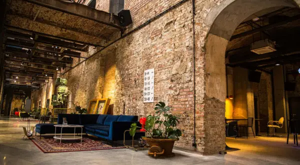 Wnętrze hotelu Cukrownia Żnin: industrialny klimat, ceglane ściany, wygodna granatowa sofa i zabytkowa maszyna.