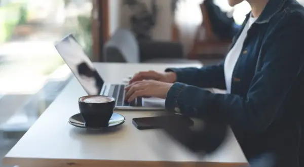 Kobieta pracuje zdalnie przy laptopie, popijając kawę. Nowy kodeks pracy reguluje takie formy zatrudnienia.