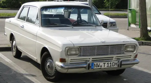 Vit Ford Taunus 12M från 1960-talet parkerad utomhus. Bilen har en klassisk design med kromade detaljer.
