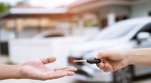 Une main tend une clé de voiture à une autre main ouverte. Idéal pour une assurance conducteur occasionnel.