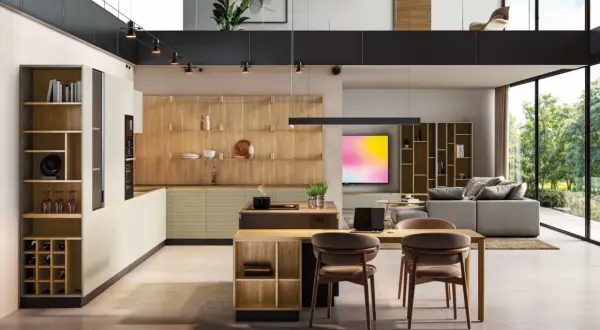 Moderna cocina con ventanal, estanterías de madera y una isla central. El espacio se abre a un salón con sofá y vistas al exterior.