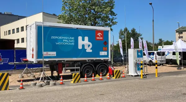 Naczepa z napisem "Zeroemisyjne paliwo wodorowe" i dystrybutor H₂. Wodór jako paliwo przyszłości.
