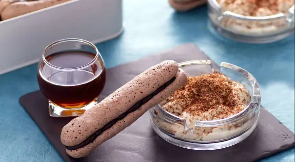 Delicioso mousse de café con bizcochos alargados y un vaso de licor.