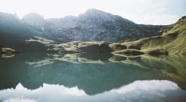 Spokojne jezioro odbija skaliste góry w Niemczech.