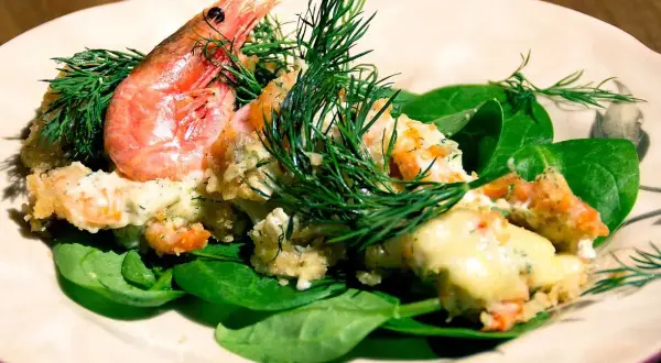 En krämig räkröra med dill, serverad på färsk spenat. Perfekt som sallad till pajen.