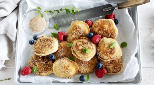 Små, gyllene krabbelurer, strösslade med socker och kanel, serveras med färska bär. Ett enkelt krabbelurer recept för fika.