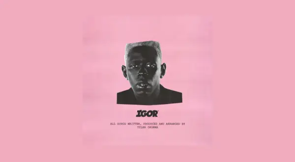 Okładka albumu "IGOR" Tylera, The Creatora. Czarno-białe zdjęcie artysty na różowym tle.
