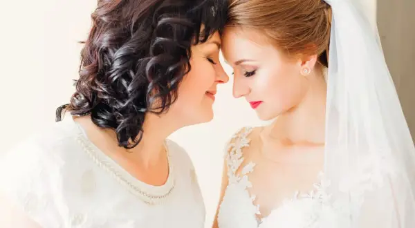 Mama i córka, obie elegancko na ślub córki, dzielą wzruszającą chwilę.