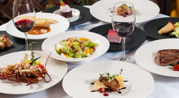 Elegancka kolacja w stylu kuchnia francuska: homar, stek, sałatka Cezar, desery i czerwone wino.