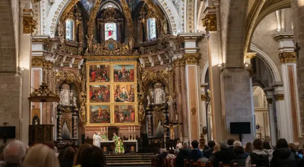 Nabożeństwo w bogato zdobionej katedrze z wiernymi siedzącymi w ławkach.
