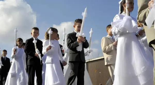 Kinder in festlicher Kleidung, oft weiße Kleider und Anzüge, tragen Kerzen zur Kommunion. Als Gast zur Kommunion zieht man sich festlich, aber dezent an.
