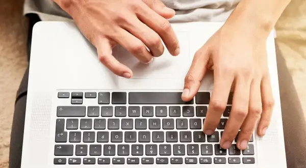 Dłonie na klawiaturze laptopa. Dowiedz się, jak odblokować klawiaturę w laptopie, gdy przestanie reagować.