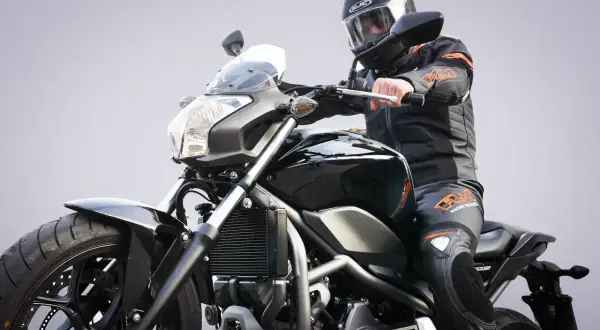 Motocyklista w kasku i kombinezonie siedzi na czarnym motocyklu. Zastanawiasz się, prawo jazdy a1 od ilu lat?