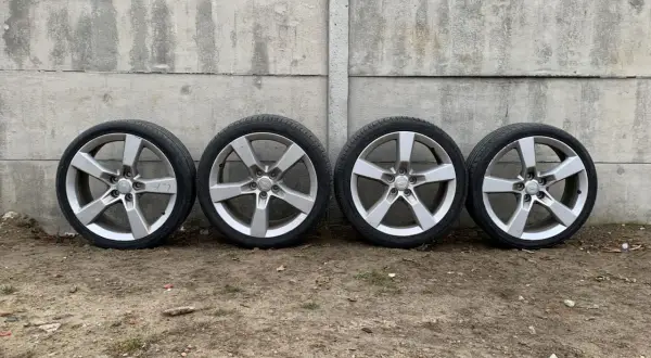 Cztery aluminiowe felgi z oponami Camaro SS na tle betonowego muru.