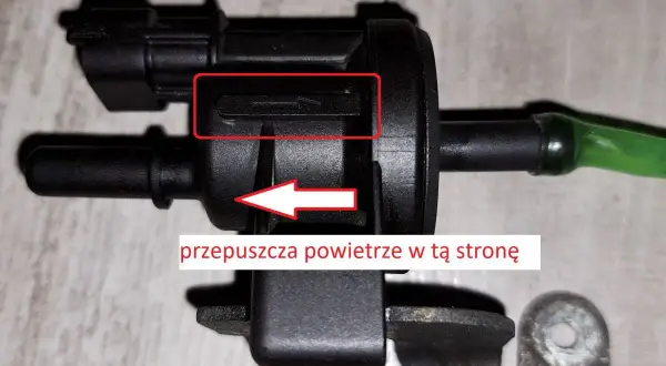 Zawór podciśnienia, potencjalna przyczyna DTC P0172 w Volkswagen. Strzałka wskazuje kierunek przepływu powietrza.