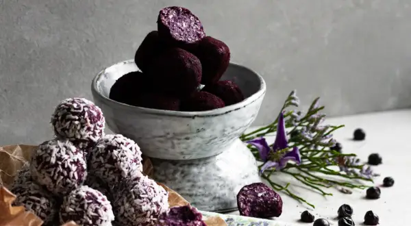 Läckra chokladbollar recept med blåbär och kokos. En skål med mörka bollar och en hög med kokosbollar.
