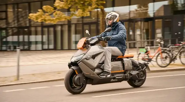 Mężczyzna w kasku jedzie na futurystycznym skuterze BMW CE04 po mieście.