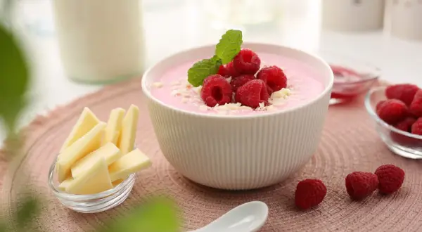 Różowy deser z malinami i miętą, obok ser i mleko. Czy pudding jest zdrowy? Zależy od składników!