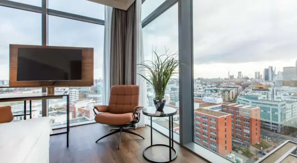 Wygodny fotel i telewizor w pokoju hotelowym z widokiem na panoramę Frankfurtu. Frankfurt Radisson Blu oferuje wspaniałe widoki.