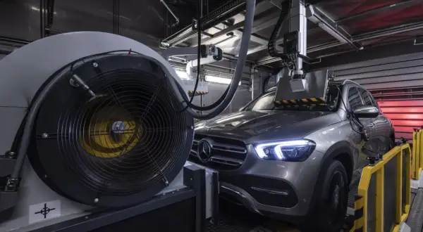 Szary Mercedes na hamowni, przygotowany do testów. Wiatrak chłodzący i mechanizm pomiarowy sugerują badanie osiągów silnika, być może wariantów tdi.