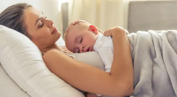 Mama i dziecko śpią wtuleni w siebie. To piękny moment kangurowania, pełen miłości i spokoju.