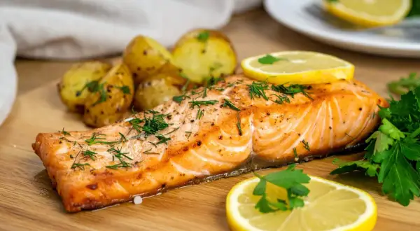 Soczysty łosoś z airfryer, podany z pieczonymi ziemniaczkami i cytryną, posypany świeżym koperkiem.