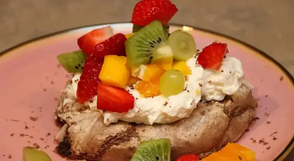 En chokladpavlova med vispgrädde och färsk frukt som jordgubbar, kiwi och mango. En härlig dessert!