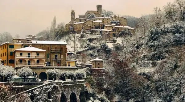 Borgo innevato in Toscana. Case antiche e alberi coperti di neve creano un paesaggio fiabesco, dimostrando che sì, a volte fa neve in Toscana.