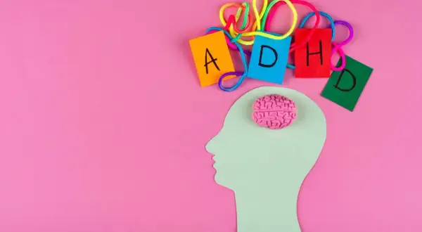 Sagoma di testa con cervello rosa e lettere colorate che formano ADHD, per capire come diagnosticarla.