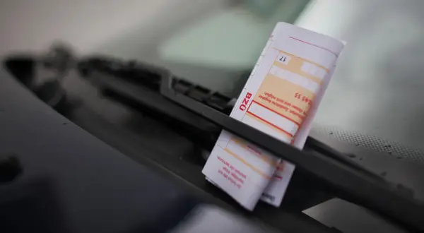 Ein Zettel am Auto wegen Parken liegt unter dem Scheibenwischer.