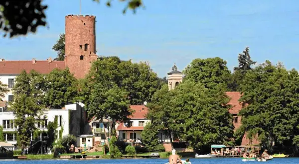 Widok na zamek i jezioro w jednym z malowniczych miast w lubuskim. Ludzie relaksują się na łodziach.