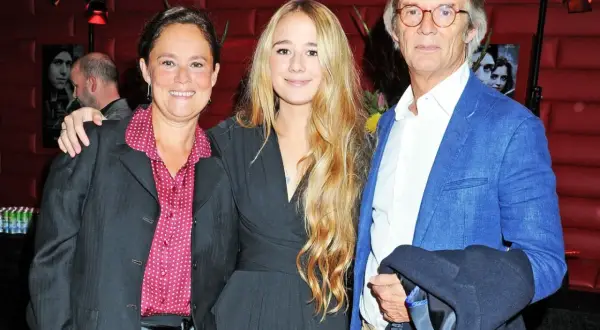 Bille Augusts barn, en kvinna och en ung flicka, poserar med en man i blå kavaj.