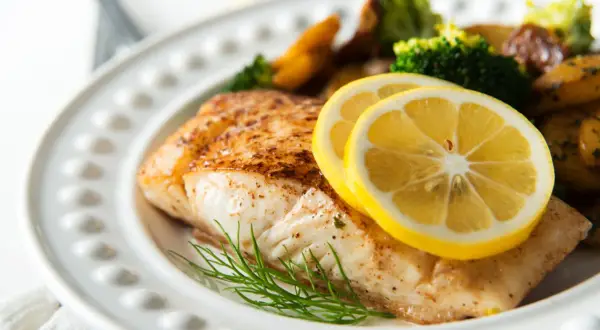 Pieczony halibut z cytryną i koperkiem, podany z pieczonymi ziemniakami i brokułami. Zdrowy posiłek, który nie przekracza halibut kcal.